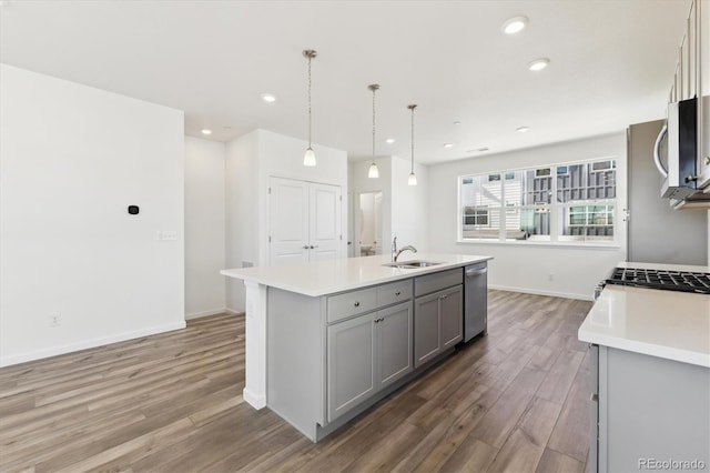 kitchen featuring gray cabinetry, wood finished floors, a sink, light countertops, and appliances with stainless steel finishes