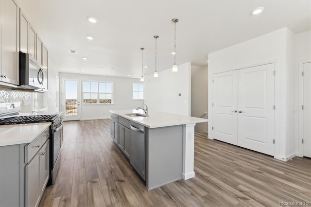 kitchen with appliances with stainless steel finishes, gray cabinets, light countertops, and a sink