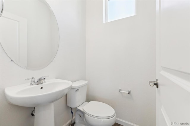 half bathroom featuring toilet and baseboards