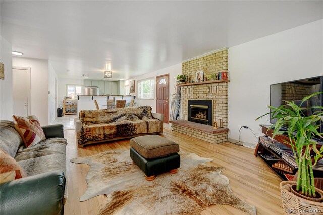 living room with a brick fireplace and light wood finished floors