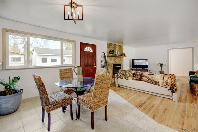 dining area with a chandelier, a brick fireplace, and tile patterned floors