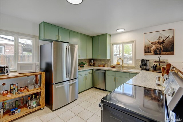kitchen featuring green cabinetry, stainless steel appliances, a sink, and backsplash