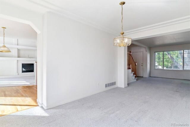 unfurnished living room featuring built in shelves, a notable chandelier, and carpet