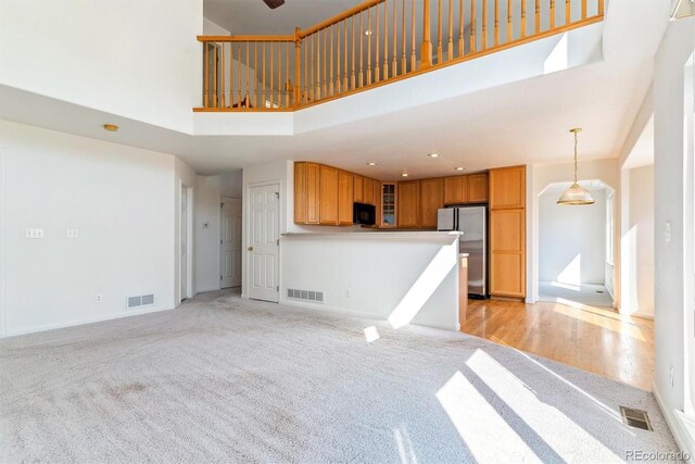 unfurnished living room featuring light hardwood / wood-style floors and a high ceiling