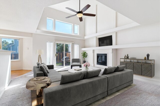 living room with a high ceiling, light wood-type flooring, and ceiling fan