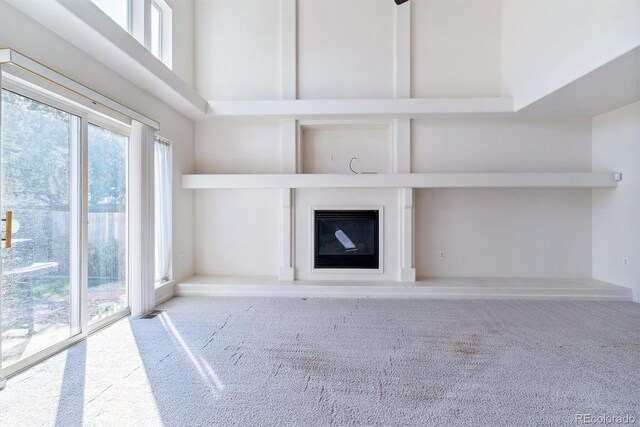 unfurnished living room featuring a towering ceiling and light colored carpet