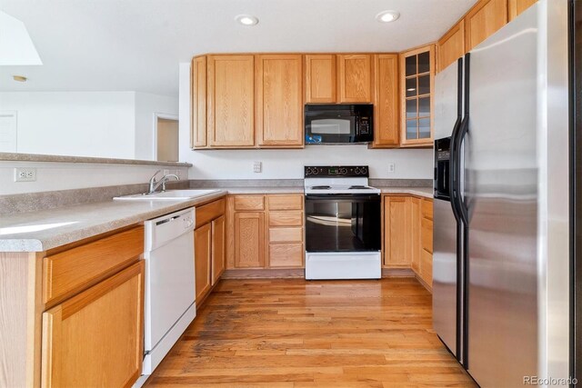 kitchen featuring light brown cabinetry, sink, light hardwood / wood-style floors, and white appliances