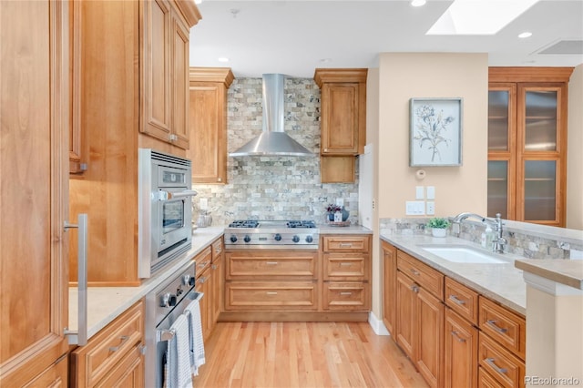 1824 Pearl St Unit B, Boulder, CO 80302 - kitchen with stainless steel appliances, wall chimney range hood, a skylight, light wood-style floors, and tasteful backsplash