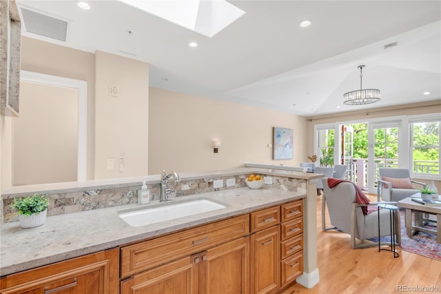 1824 Pearl St Unit B, Boulder, CO 80302 - kitchen featuring light wood finished floors, a skylight, light stone countertops, hanging light fixtures, and recessed lighting