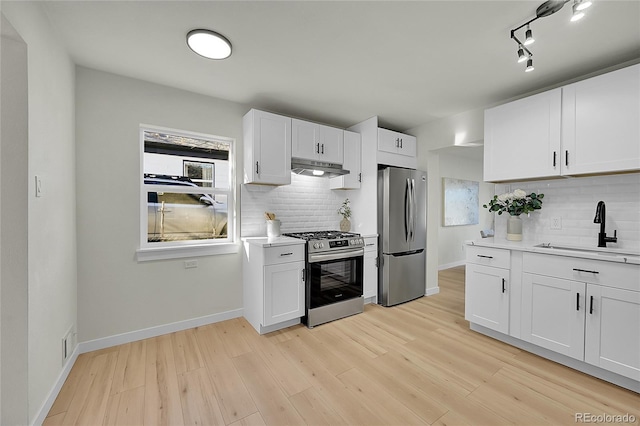 kitchen featuring light hardwood / wood-style floors, appliances with stainless steel finishes, tasteful backsplash, white cabinets, and sink