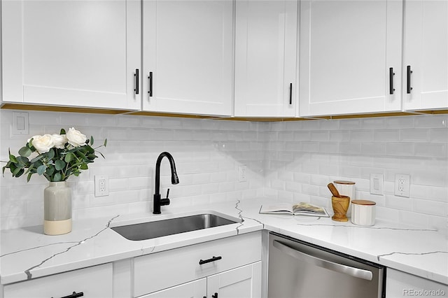 kitchen featuring tasteful backsplash, stainless steel dishwasher, sink, white cabinetry, and light stone counters