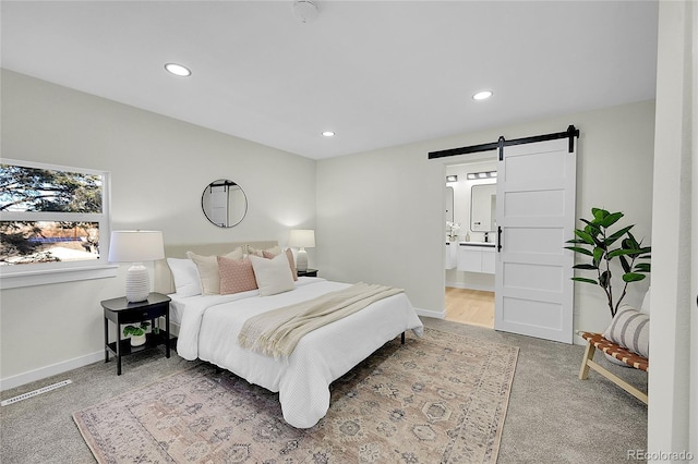 bedroom featuring ensuite bathroom, a barn door, and carpet flooring