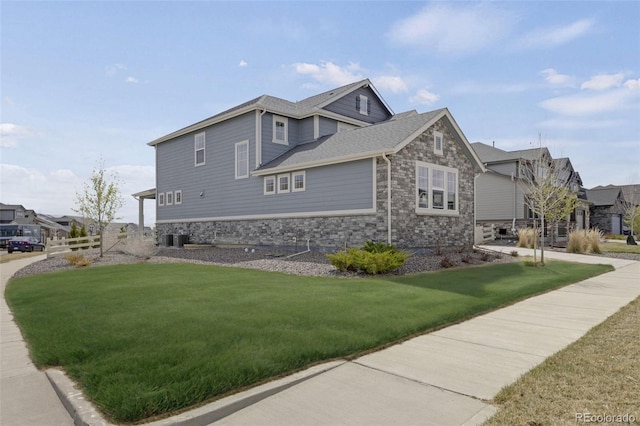 6802 S Uriah St, Aurora, CO 80016 - view of side of property with stone siding, a lawn, and central AC