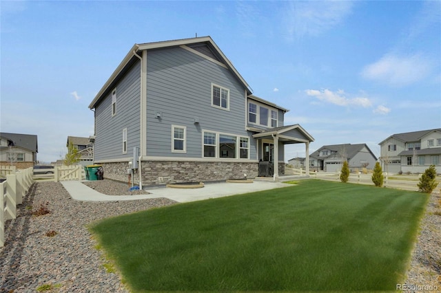 6802 S Uriah St, Aurora, CO 80016 - rear view of house featuring stone siding, a patio area, and a residential view