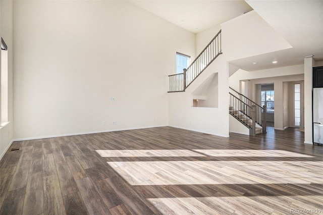 unfurnished living room with a towering ceiling and hardwood / wood-style flooring