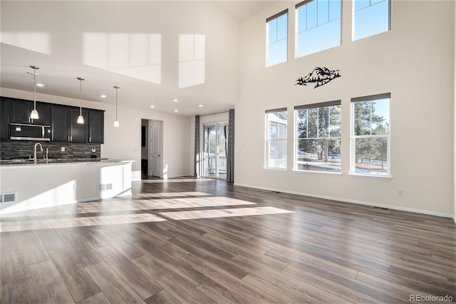 unfurnished living room with a high ceiling, dark hardwood / wood-style flooring, and plenty of natural light