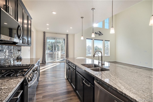 kitchen featuring sink, dark wood-type flooring, hanging light fixtures, decorative backsplash, and appliances with stainless steel finishes