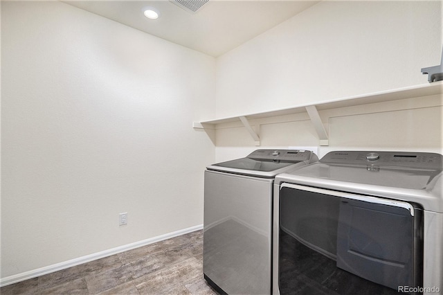 clothes washing area with hardwood / wood-style flooring and washing machine and dryer