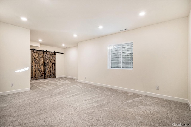 basement featuring a barn door and light carpet