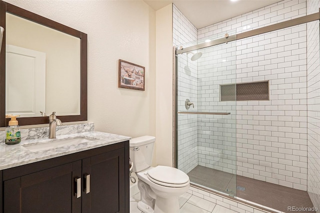 bathroom with toilet, vanity, tile patterned floors, and an enclosed shower