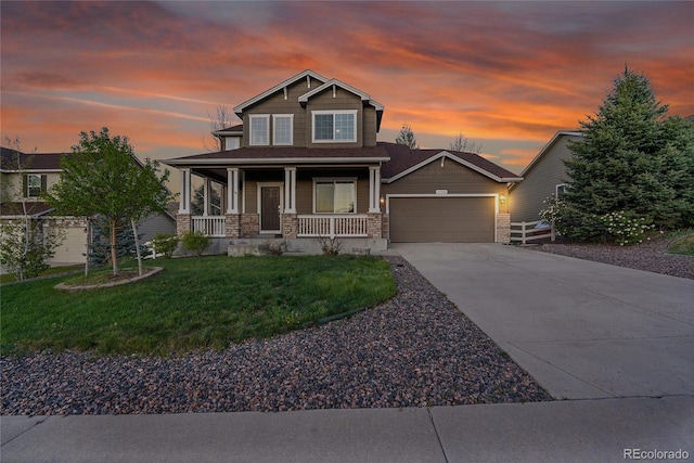 craftsman-style home with a porch, a garage, stone siding, concrete driveway, and a yard