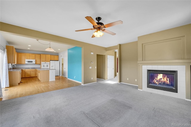 unfurnished living room featuring light carpet, a ceiling fan, baseboards, a tiled fireplace, and recessed lighting