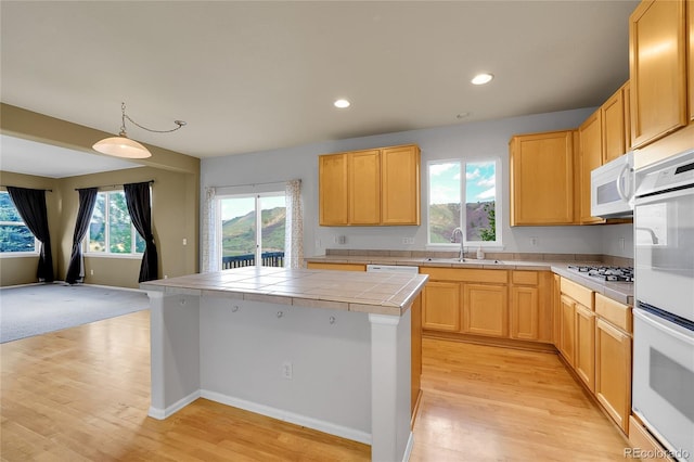 kitchen featuring tile countertops, white appliances, a sink, light wood-style floors, and light brown cabinets