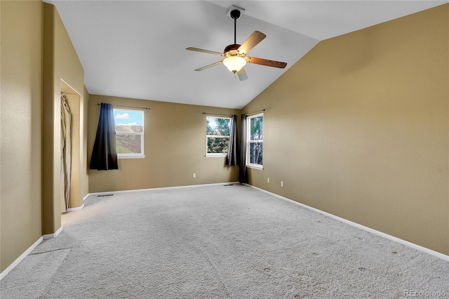 empty room featuring a ceiling fan, lofted ceiling, light carpet, healthy amount of natural light, and baseboards