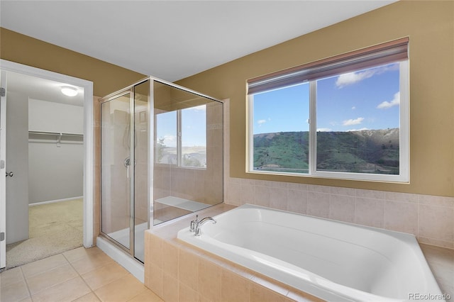 full bathroom featuring a stall shower, tile patterned flooring, a spacious closet, and a bath