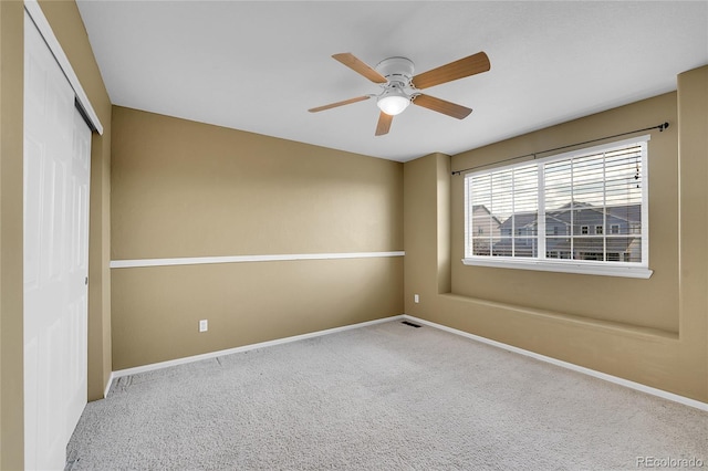 spare room with carpet, a ceiling fan, and baseboards