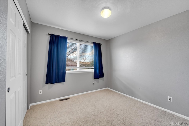 carpeted empty room featuring baseboards