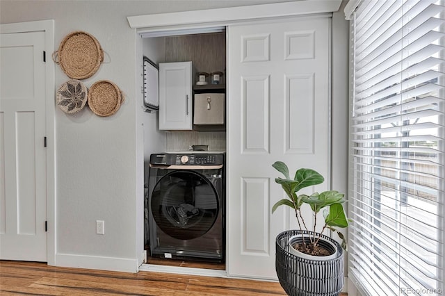 10042 Hudson St, Thornton, CO 80229 - laundry area featuring washer / dryer, cabinet space, light wood-type flooring, and baseboards