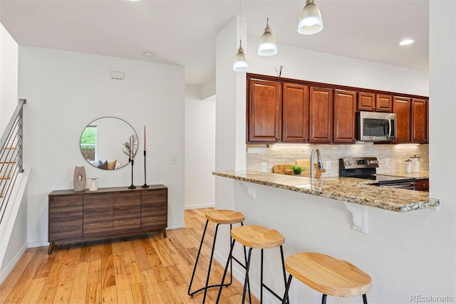 4190 W Alameda Ave, Denver, CO 80219 - kitchen featuring appliances with stainless steel finishes, a breakfast bar area, decorative backsplash, light stone counters, and recessed lighting