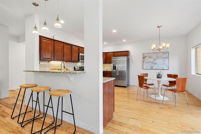 4190 W Alameda Ave, Denver, CO 80219 - kitchen with stainless steel appliances, a kitchen bar, tasteful backsplash, light wood-type flooring, and recessed lighting