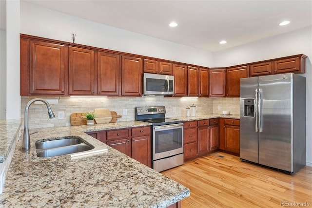 4190 W Alameda Ave, Denver, CO 80219 - kitchen featuring appliances with stainless steel finishes, a sink, light stone counters, light wood finished floors, and recessed lighting
