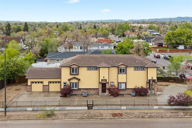 4190 W Alameda Ave, Denver, CO 80219 - view of front of house featuring a fenced front yard, concrete driveway, a residential view, a mountain view, and an attached garage