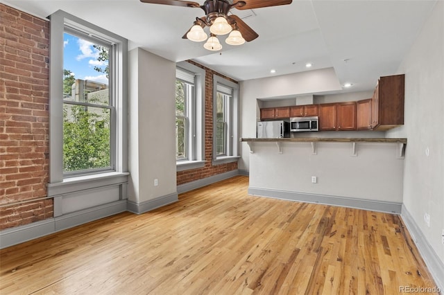 3211 Zuni St Unit 9, Denver, CO 80211 - kitchen featuring stainless steel appliances, brown cabinets, light wood-type flooring, a kitchen bar, and healthy amount of natural light
