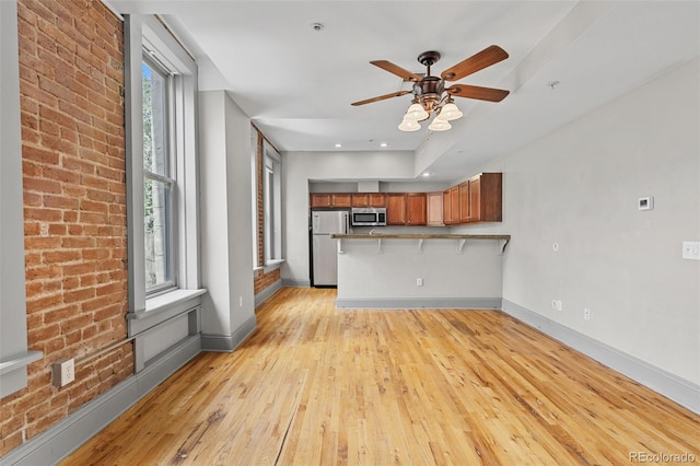 3211 Zuni St Unit 9, Denver, CO 80211 - kitchen featuring appliances with stainless steel finishes, brown cabinetry, a peninsula, light wood-style floors, and a breakfast bar area