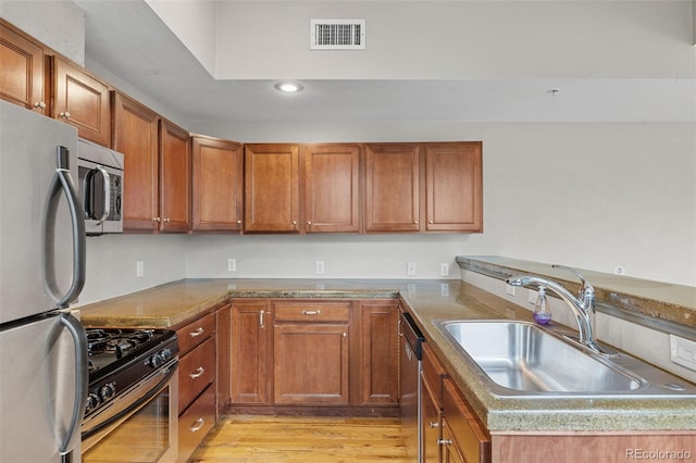 3211 Zuni St Unit 9, Denver, CO 80211 - kitchen with stainless steel appliances, brown cabinets, recessed lighting, light wood-style floors, and a peninsula
