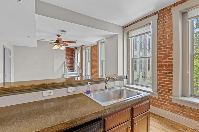 3211 Zuni St Unit 9, Denver, CO 80211 - kitchen featuring brick wall, light wood-type flooring, dark countertops, ceiling fan, and dishwashing machine