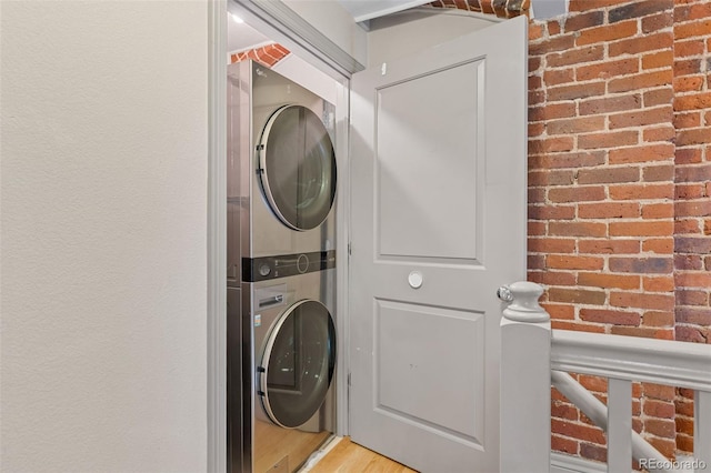 3211 Zuni St Unit 9, Denver, CO 80211 - laundry area with stacked washer and clothes dryer, light wood-type flooring, and brick wall
