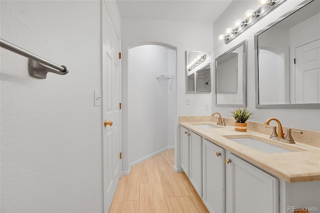 full bath with double vanity and baseboards