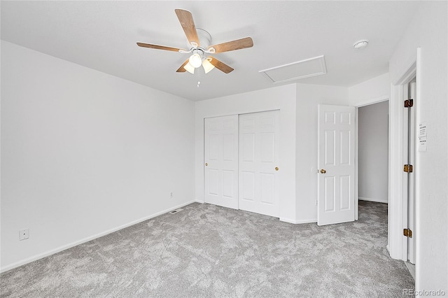 unfurnished bedroom featuring carpet flooring, baseboards, a closet, ceiling fan, and attic access