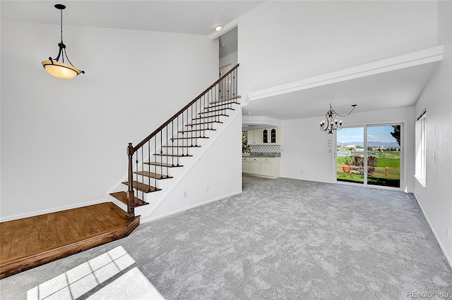 unfurnished living room featuring stairs, a chandelier, carpet floors, baseboards, and a high ceiling