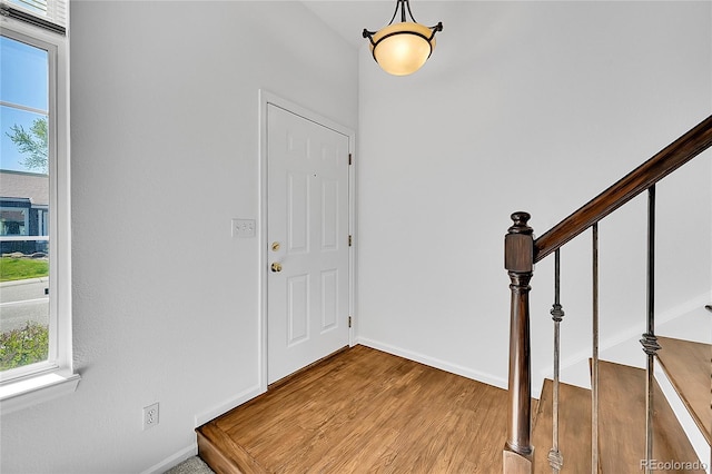 entrance foyer with healthy amount of natural light, wood finished floors, stairway, and baseboards