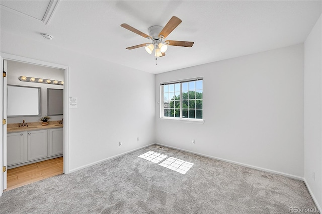 unfurnished bedroom with light colored carpet, baseboards, ensuite bath, and ceiling fan