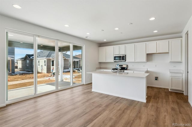 kitchen featuring an island with sink, stainless steel appliances, light hardwood / wood-style floors, and white cabinets