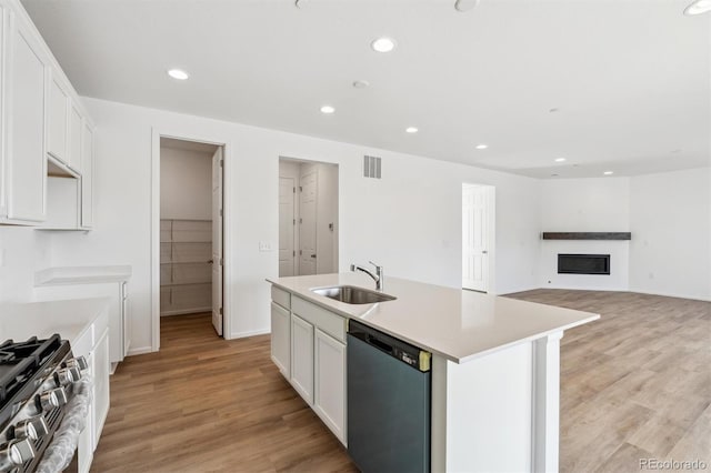 kitchen featuring sink, light hardwood / wood-style flooring, appliances with stainless steel finishes, a kitchen island with sink, and white cabinets