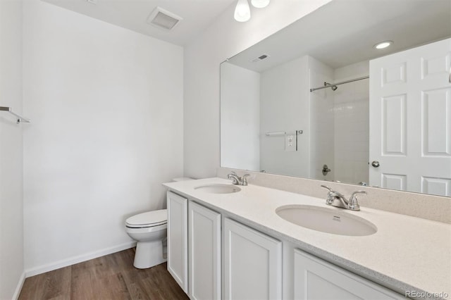 bathroom with vanity, hardwood / wood-style flooring, toilet, and a tile shower