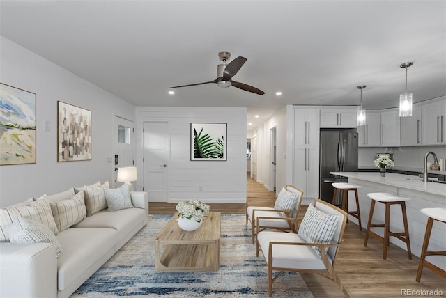 living room with light wood-type flooring, recessed lighting, and a ceiling fan